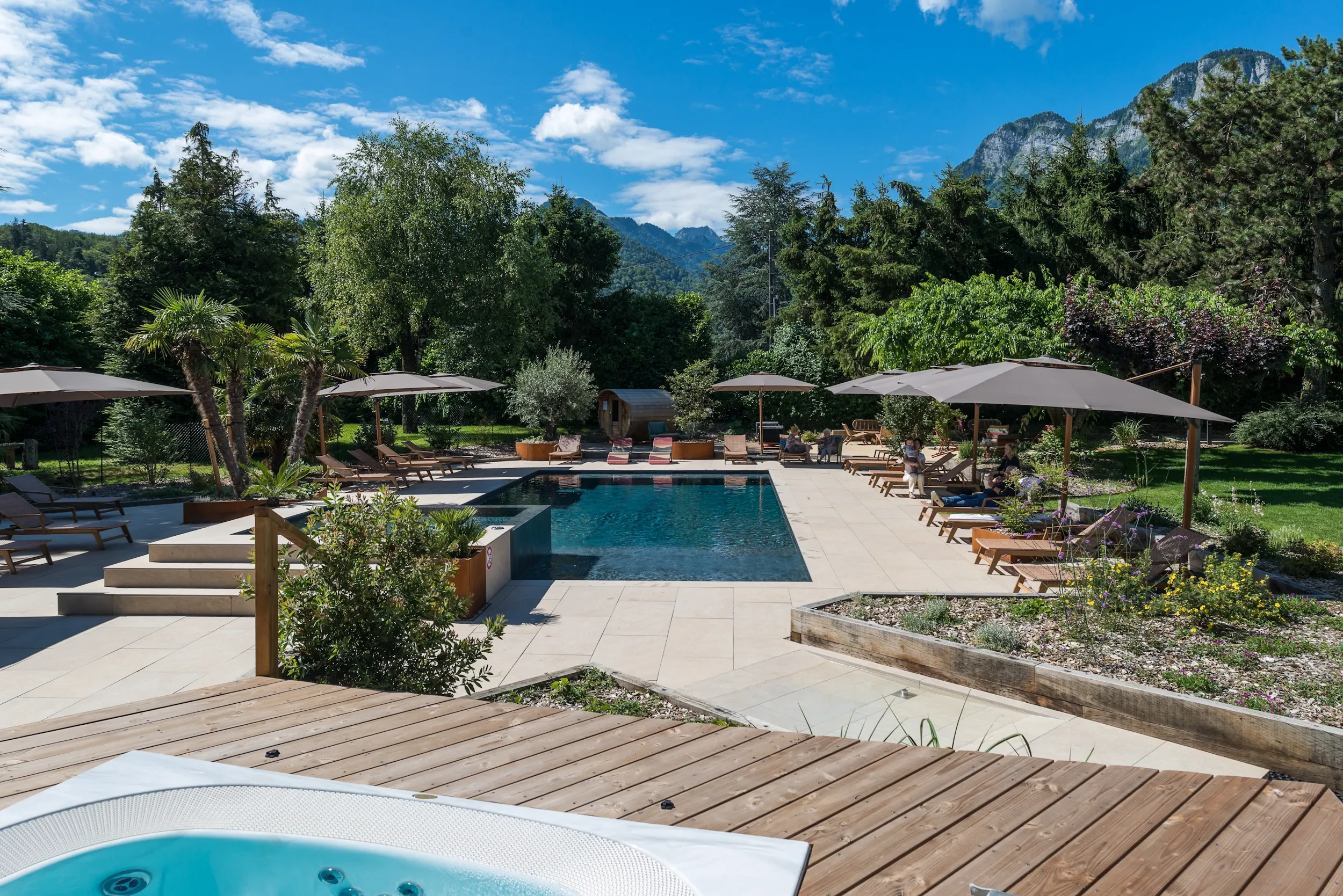Piscine extérieure entourée de chaises longues et parasols, Hôtel spa proche du Lac d’Annecy - L'Arcalod